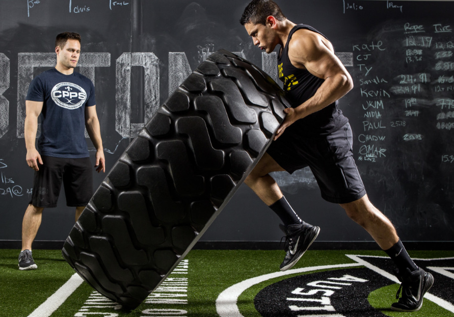 Athelete pushing a huge tire end over end